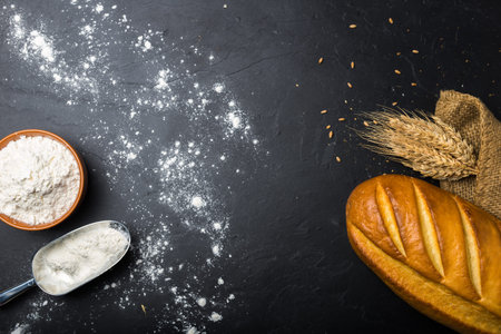 Loaf of bread and wheat flour on slate