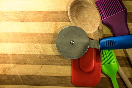Pizza cutter, wooden spoon, silicone brushes with bamboo wooden boardの写真素材