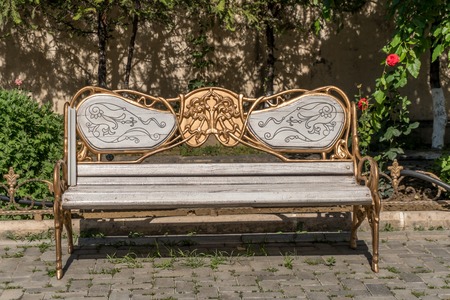 Antique wood and metallic decorated bench at a park. Golden decorated ornaments.の写真素材