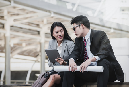 Smiling young business woman and handsome businessman discussing something positive and using a digital tablet together,Business Concept, Together Conceptの写真素材