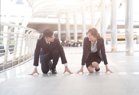 Businessman and businesswoman ready for race in business with on city street background.の写真素材