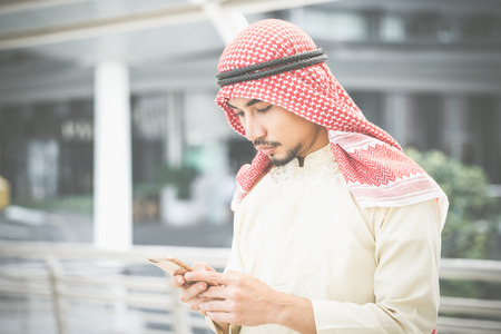 Arab businessman working with his phone  behind the office building.の写真素材