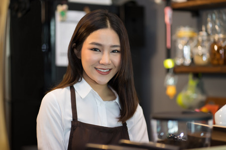 Portrait Beautiful young owner barista  looking happy and smiling at the camera ,Working in a cafe.の写真素材