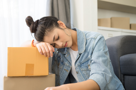 Tired young Asian casual woman working small business online packing her sleep ,  overworked, lazy to work. Teenager business owner work at home. Small business owner concept.の写真素材