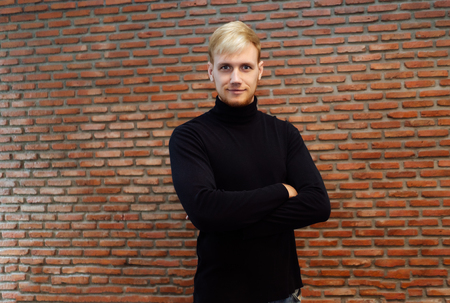 Portrait of Handsome young man in black sweater against on bricks wall backgroundの写真素材