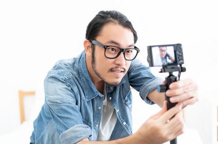 Young Asian blogger setting camera video with recording filming at homeの写真素材