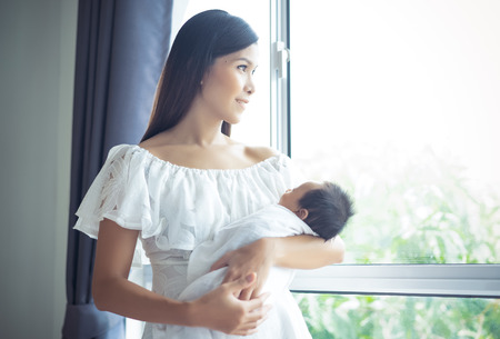 Young Asian mother holding newborn baby the sleeping on the arm her, maternity concept, soft image of beautiful familyの写真素材