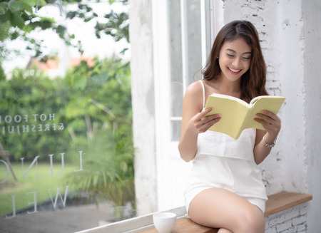 Portrait of cafe city lifestyle woman sitting in trendy urban cafe reading interesting book in cafeの写真素材