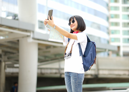 Young Asian woman making picture of herself, selfie on the street. Filtered image.の写真素材