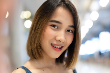 Closeup portrait of caucasian Asian lady wearing dress jeans smilling and taking selfie at airport.