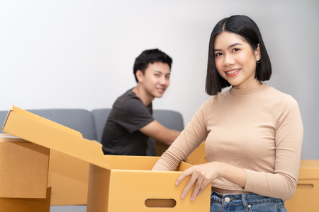 Young Asain couple unpacking cardboard boxes in new home at  at a moving day at looking at camera.Moving house.Real estate.の写真素材