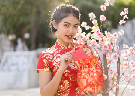 Young Asian woman in red dress traditional cheongsam holding red envelopes for lucky. Happy Chinese New Year Festival Concept.の写真素材