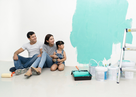 Happy multiethnic family renovating their new home, they are sitting together and smiling and look at the colors on the walls with happiness.の写真素材