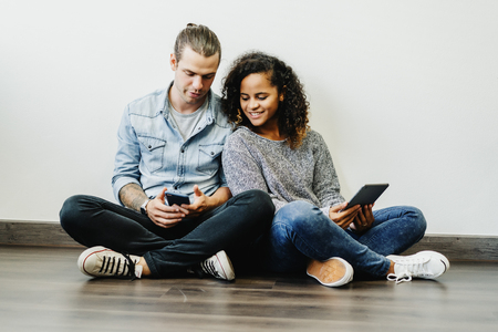 Smiling young multiethnic couple using digital tablet together at home. People, communication and dating conceptの写真素材