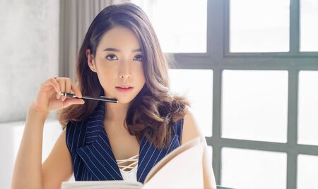 Beautiful business Asian lady is looking at camera while working in officeの写真素材