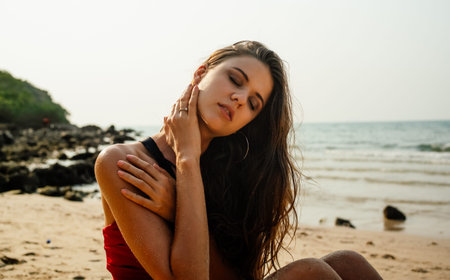 Close-up beautiful sexy young suntanned woman posing in seductive energetic posture in sandy beach....