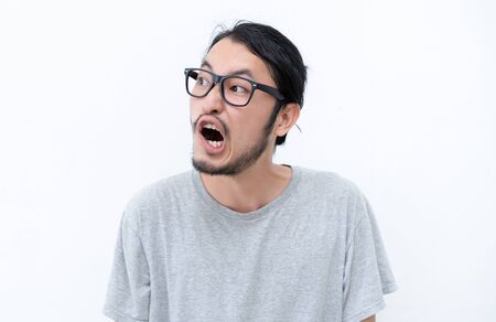 Portrait of a funny hipster Asian man looking away isolated on white background. Emotion, facial expression and people concept.の写真素材
