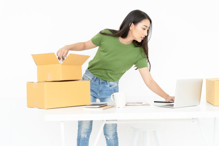 Young Asian casual woman working small business online packing product to cardboard box.Startup...