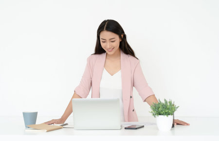 Portrait of young Asian casual woman working small business online owner standing at desk with laptop. Girl freelancer,entrepreneur works at home.Online marketing,education, e-learning, distance work.の写真素材