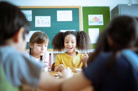 Group of Elementary School Pupils with pens and papers writing in classroom. Education, elementary school, learning and technology concept.の写真素材