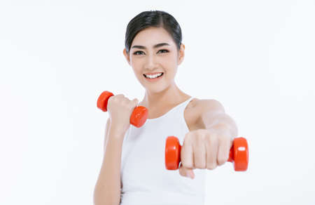 Beautiful young Asian fitness woman lifting dumbbells smiling and energetic isolated over white background. Healthy lifestyle.の写真素材