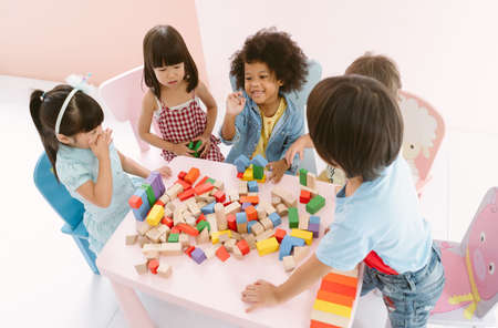 Ethnicity diversity group of kids playing with colorful blocks on table in class at the kindergarten. Kindergarten international school education concept. Top view.の写真素材