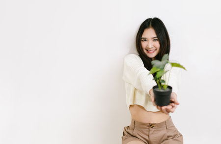 Young beautiful Asian woman smiling friendly holding flower pot on a isolated white background.の写真素材