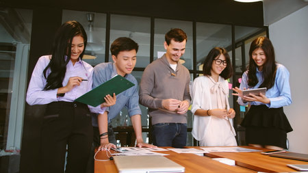 Group of business people in smart casual standing in meeting room brainstorming working together on...