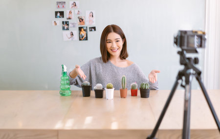 Happy Asian girl vlogger influencer smiling record video camera filming for live sell and talking...