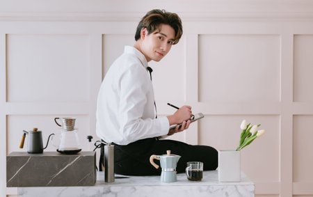 Portrait of Asian barista man wearing uniform korean holding digital tablet and looking at camera...