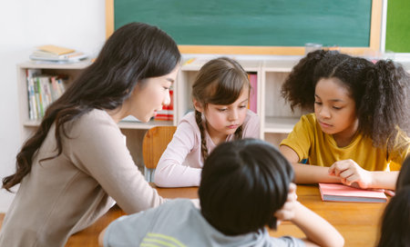 Multiethnic group of Elementary School pupils sit on chair in circle around with Asian female teacher reading book, learning, discussing new things in classroom. Education, elementary school concept.の写真素材
