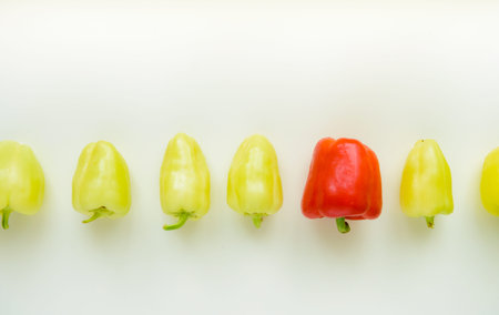 Red pepper standing between with green peppers