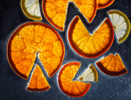 transparent slices of fresh oranges and lemons on the glassの写真素材