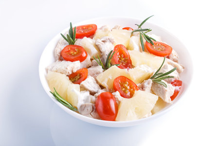 Chicken fillet salad with rosemary, pineapple and cherry tomatoes isolated on whiteの写真素材