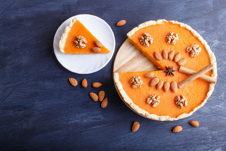 Traditional american sweet pumpkin pie decorated with nuts, on dark blue wooden background. top view, copy space.の写真素材
