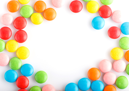 Colorful frame of multicolored chocolate candy dragees isolated on white background. Copy space. Top viewの写真素材