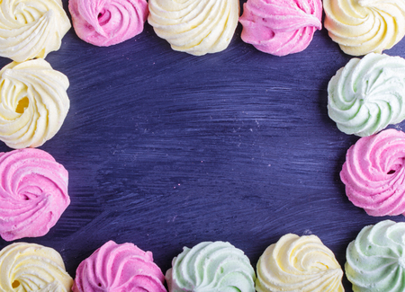 Colorful frame of multicolored meringues on black wooden background. copy space, top view, flat lay.の写真素材