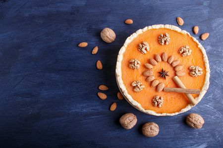 Traditional american sweet pumpkin pie decorated with nuts, on dark blue wooden background. top view, copy space.の写真素材