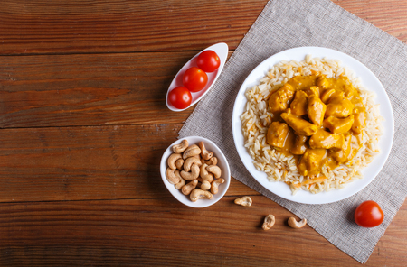 Rice with chicken curry sauce with cashew on brown wooden background. top view, copy space.の写真素材