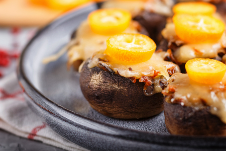 Stuffed fried champignons with cheese, kumquats and green peas on a gray concreteの写真素材