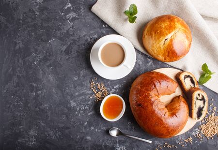 Homemade yeast buns and rolls with poppy seeds and honey on a black concreteの写真素材
