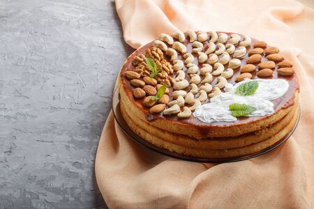 Homemade cake with caramel cream and nuts on a gray concreteの写真素材