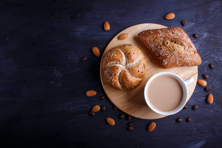 Cup of coffee with cream  and buns on a black background. top view, flat lay, copy space.