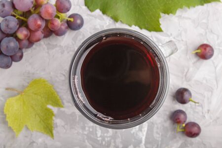 Glass of red grape juice on a gray concrete background. Morninig, spring, healthy drink concept. Top view, close up, flat lay.の写真素材