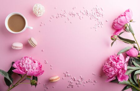 Pink peony flowers and a cup of coffee on a pink pastel background. Morninig, spring, fashion composition. Flat lay, top view, copy space.の写真素材