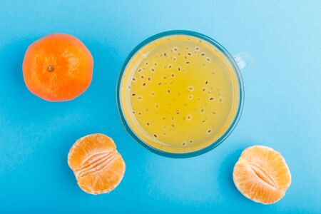 Glass of tangerine orange colored drink with basil seeds on a blue background. Morninig, spring, healthy drink concept. Top view,  close up, flat lay.の写真素材