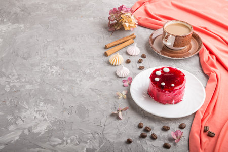 Red cake with souffle cream with cup of coffee on a gray concrete  background and red textile. side view, copy space.の写真素材