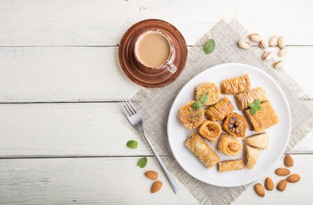 Traditional arabic sweets (kunafa, baklava)  and a cup of coffee on a white woodenの写真素材