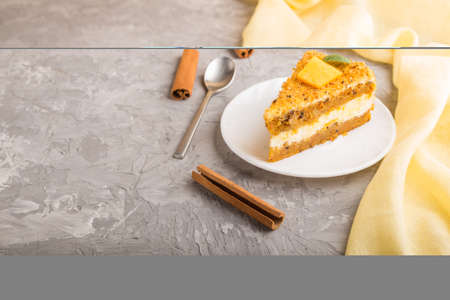 Homemade cake with persimmon and pumpkin on a gray concrete background with yellow textile. side...
