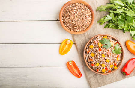 Buckwheat porridge with vegetables in wooden bowl on a white wooden background and linen textile. Top view, flat lay, copy space. Russian traditional cuisine.の写真素材